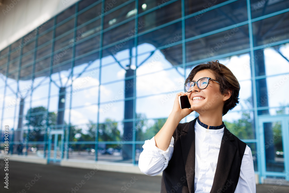 Young successful businesswoman speaking on phone, standing near business centre. Young successful businesswoman speaking on phone, standing near business centre.