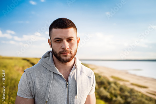 Young sportive man posing in field at sunrise.