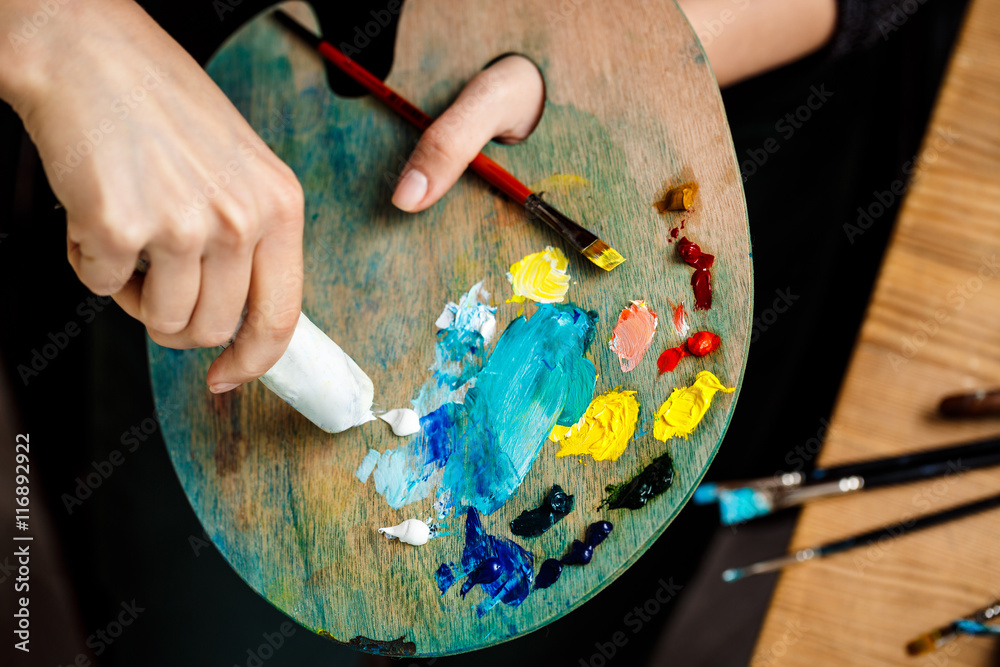 Obraz premium Close up of girl squeezing white oil paint on palette.