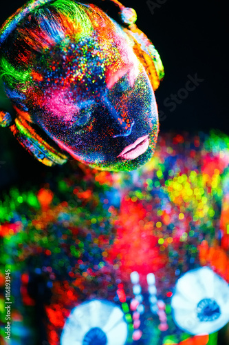 Topless girl painted in UV powder as a DJ panel.