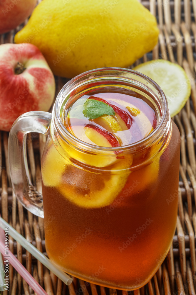Iced tea with lemon and peach in a Mason jar. Selective focus Iced tea with lemon and peach in a Mason jar. Selective focus