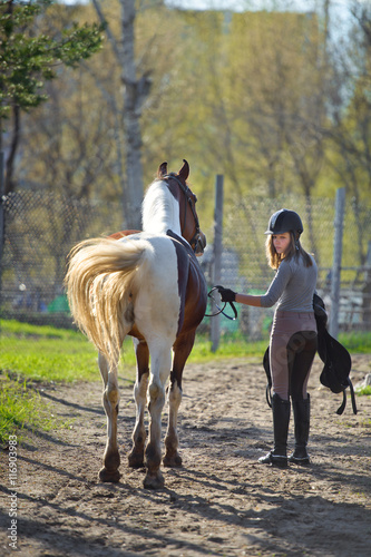 Girl sportswoman and her horse back to the stables after riding © sheikoevgeniya