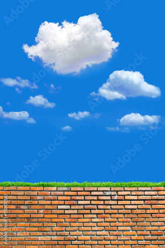 old red brick wall with grass over cloudy and blue sky background in day light