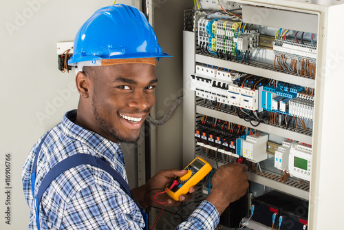 Technician Examining Fusebox With Multimeter Probe