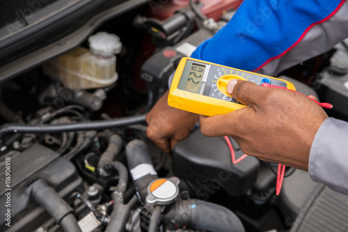 Mechanic Checking Battery With Multimeter