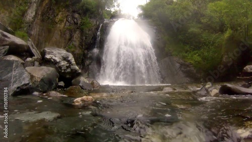 Big beautiful waterfall flows down the rocks mountains Altai in Russia.