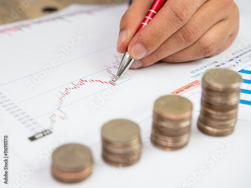 Businessman and Stack Of Coins with investment graph report