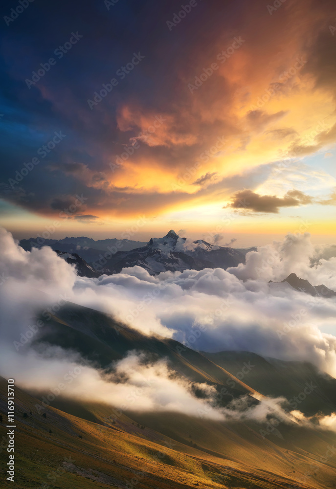 Obraz premium High mountain ridge in the clouds during sunrise. Beautiful panoramic landscape