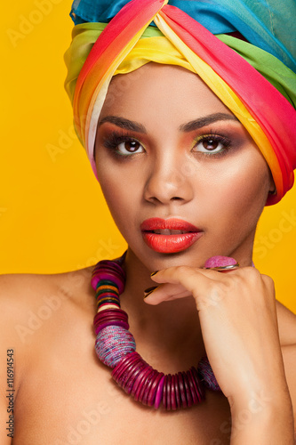 Girl with afro american ethnic turban on yellow background
