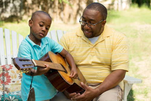 African American man teaching his son how to play the guitar © digitalskillet1