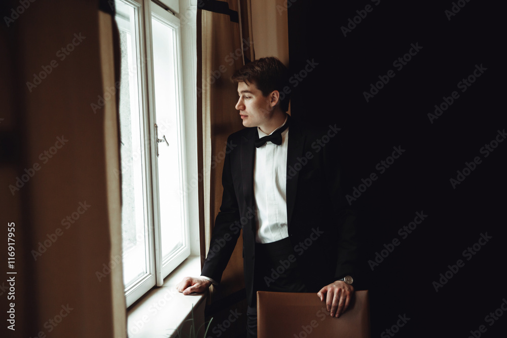 Groom stands thoughtful looking through the windod Groom stands thoughtful looking through the windod