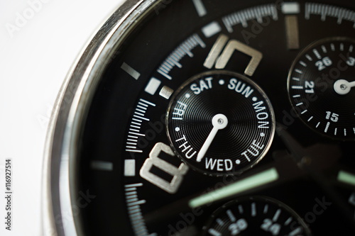 Macro detail of a silver and black watch with the focus on the rounded week calender displaying the days in week as a symbol of planning and precision 