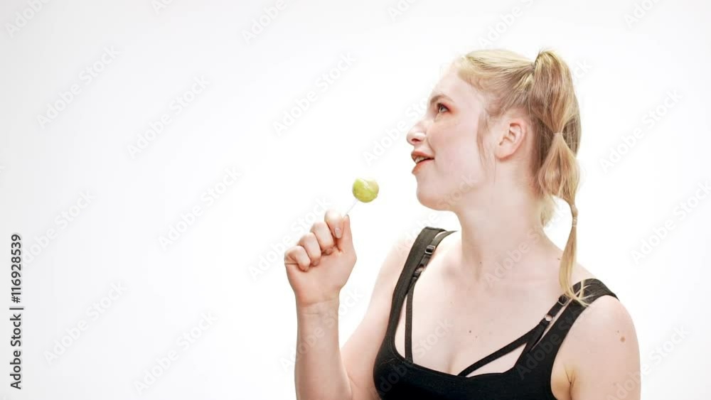Young beautiful girl dancing, smiling, holding chupa chups, singing over white background. Slow motion. Young beautiful girl dancing, smiling, holding chupa chups, singing over white background. Slow motion.