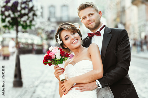 Bride and bridegroom holding bouquet and smiling