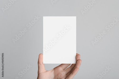 A6 Flyer / Postcard / Invitation Mock-Up - Male hands holding a blank flyer on a gray background. photo