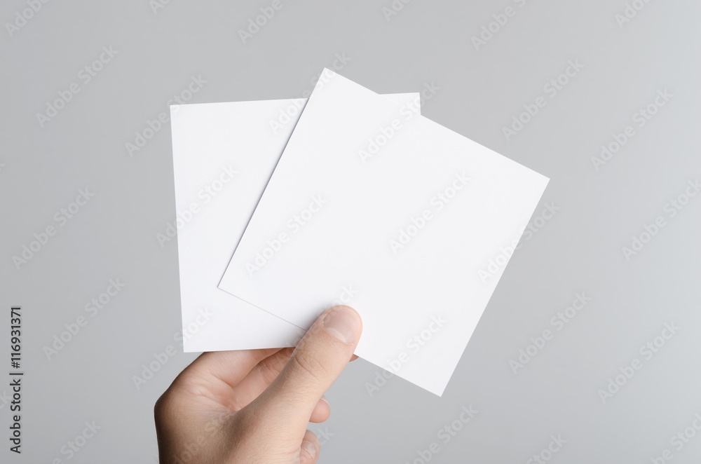 Square Flyer / Invitation Mock-Up - Male hands holding blank flyers on a gray background. Square Flyer / Invitation Mock-Up - Male hands holding blank flyers on a gray background.