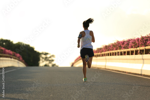 young woman runner running on city bridge road © lzf