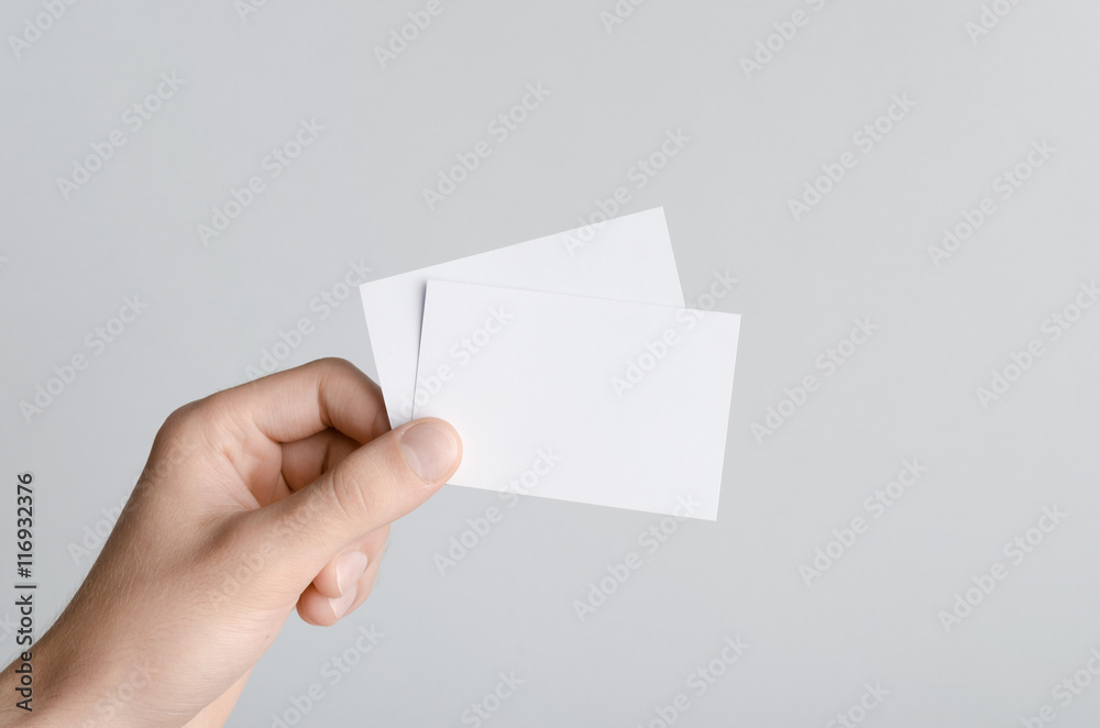 Business Card Mock-Up (85x55mm) - Male hands holding blank cards on a gray background.