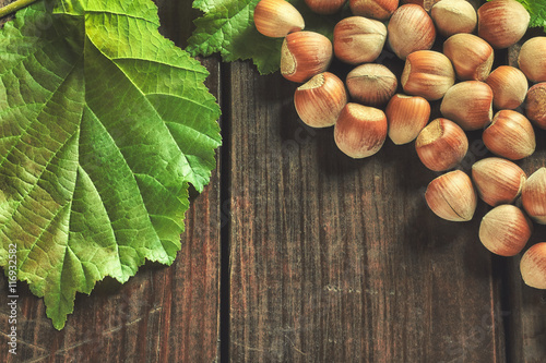 Hazelnuts and leaves on wooden background. Top view with copy space
