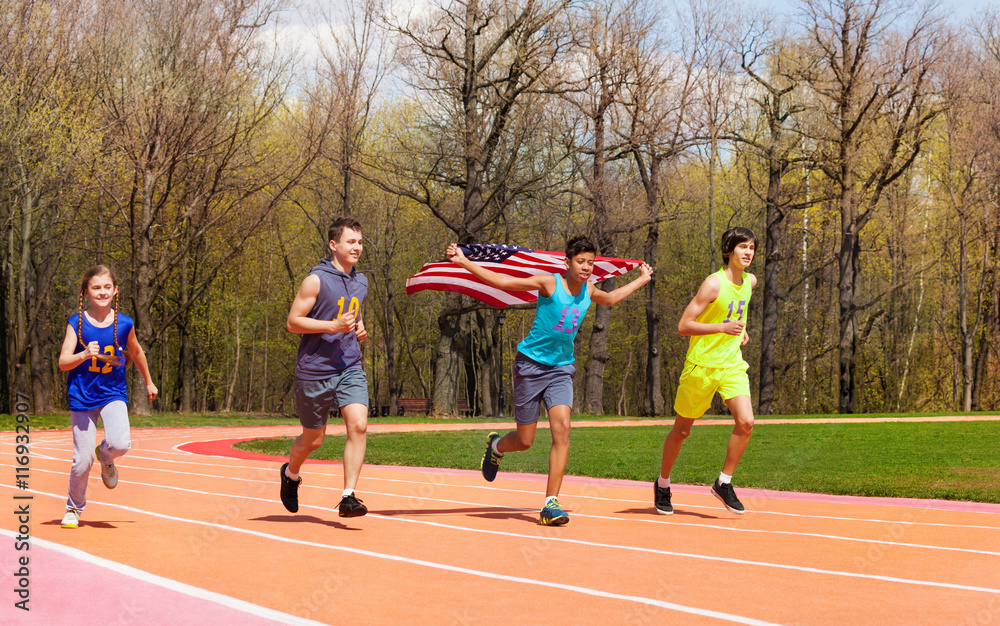 Four young sprinters waving American flag on track