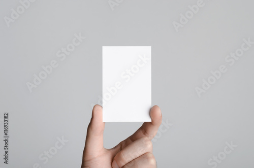 Business Card Mock-Up (85x55mm) - Male hands holding a blank card on a gray background.