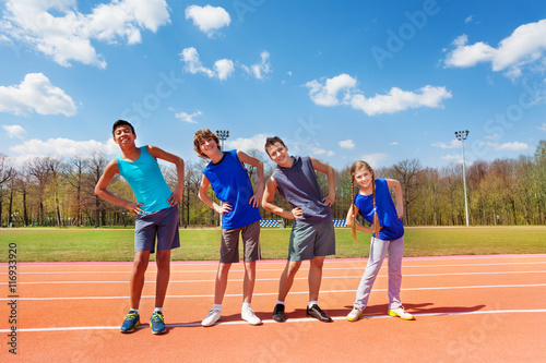 Happy teens doing side bending exercises outdoors