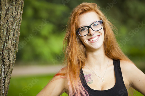 young red haired woman student relaxing learning in park sunny weather