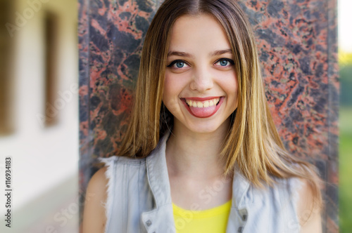 Female teenager with big blue eyes smiling and showing her tongue