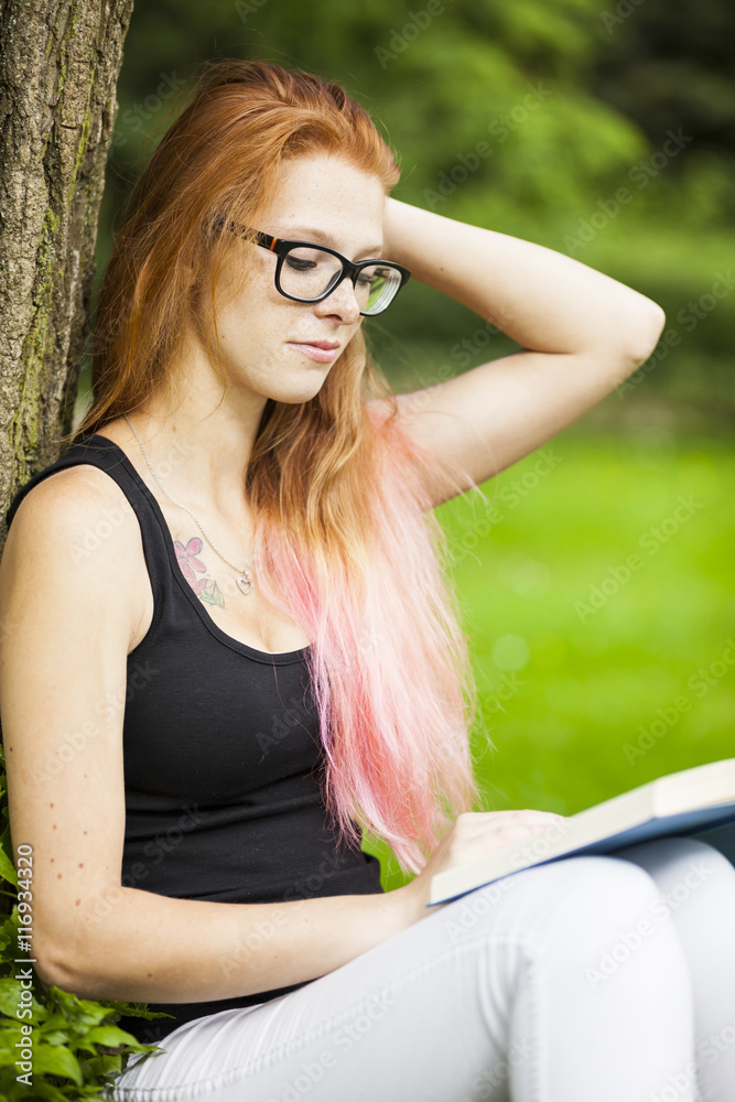 Obraz premium young red haired woman student relaxing learning in park sunny weather