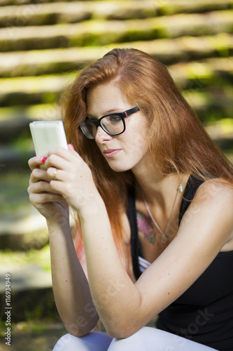 young red haired woman student relaxing learning in park sunny weather summer