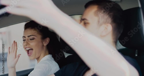Cool couple having fun singing and dancing while driving car. Charming brunette woman and handsome man spending time together