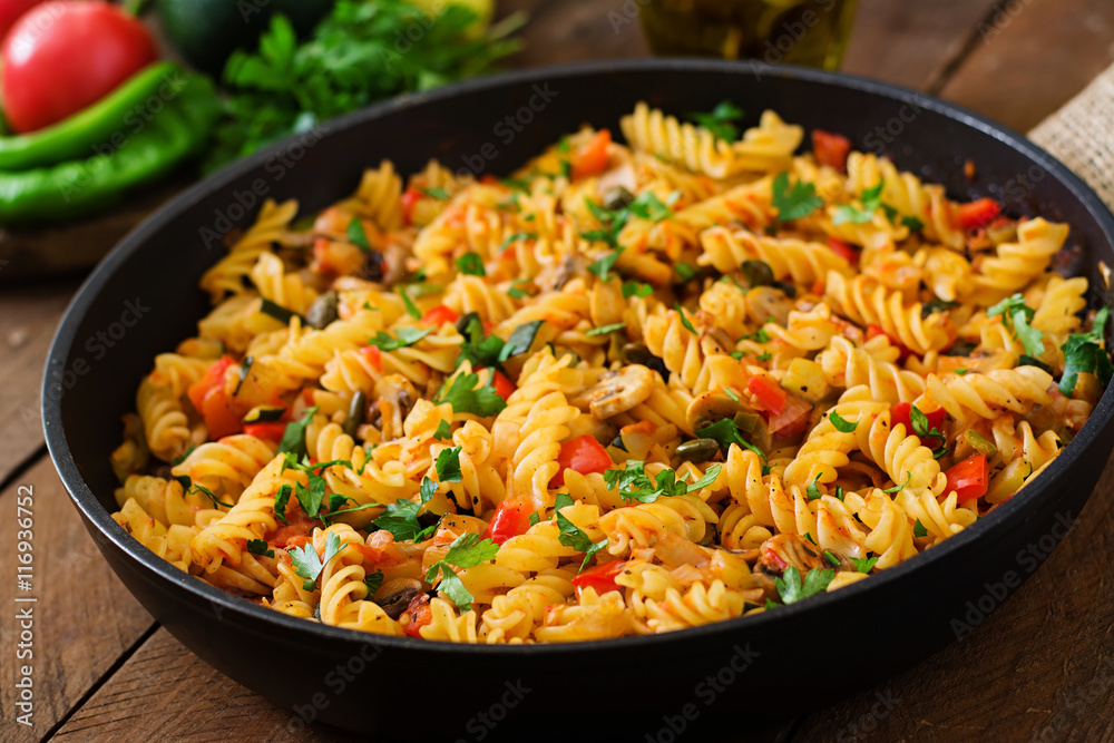 Vegetarian Vegetable pasta Fusilli with zucchini, mushrooms and capers in pan on wooden table. Vegetarian Vegetable pasta Fusilli with zucchini, mushrooms and capers in pan on wooden table.