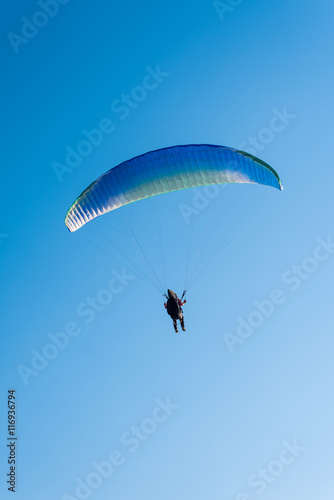 Paragliding in the sky. Man flying a paraglider on the sun.