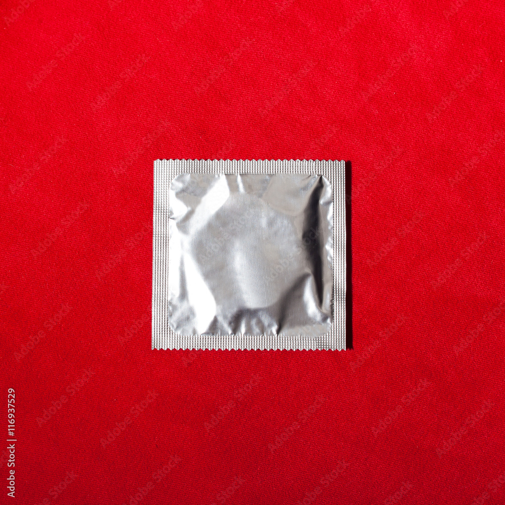 Condom on red textile background Condom on red textile background