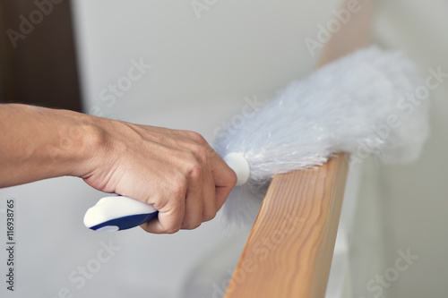 Wall Mural young man dusting the house with a microfiber duster