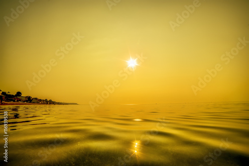 sea at sunrise  sunset  water surface. natural sea warm background. Surface of the water in the foreground. Gold paint  sun with rays over the horizon.  