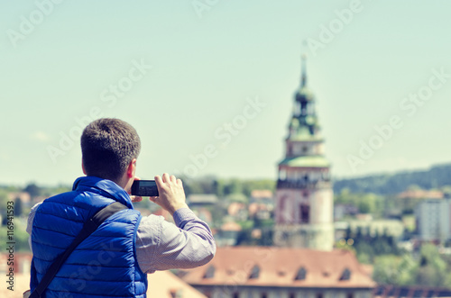 Young man making mobile camera photo of Cesky Krumlov landmark and architecture.