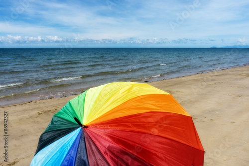 Colorful umbrella on a sunny day, sea in background © annuar83