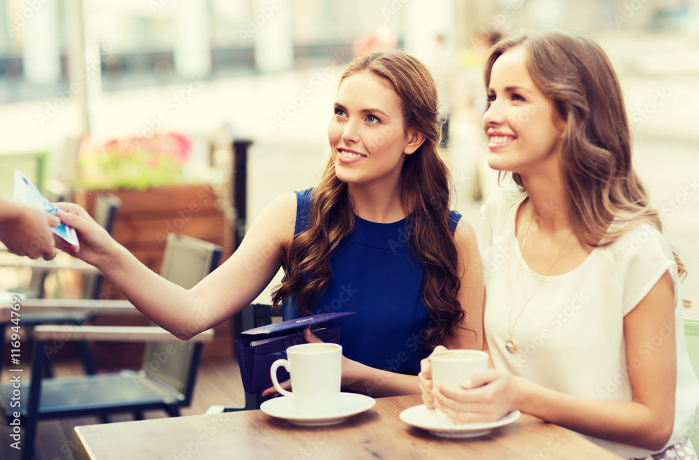 women paying money to waiter for coffee at cafe women paying money to waiter for coffee at cafe