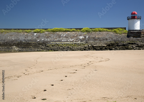 Footprints in the sand on Burry Port Beach towards the Lighthouse, Llanelli, South Wales photo
