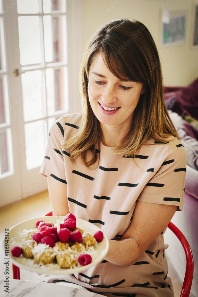 A woman holding a plate with dessert and a lit candle. A woman holding a plate with dessert and a lit candle.