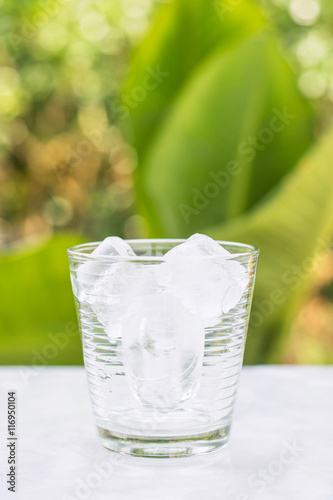 Glass with ice cubes on the table