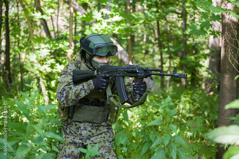 a man in a military uniform in the woods with a gun