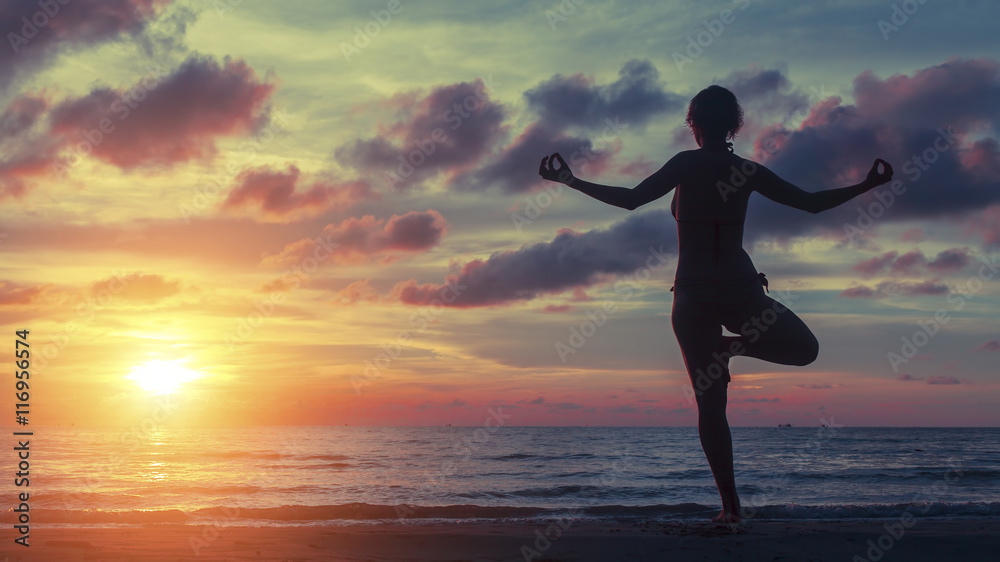 Yoga woman exercising on the beach during a stunning sunset. Peace, harmony, health and meditation.