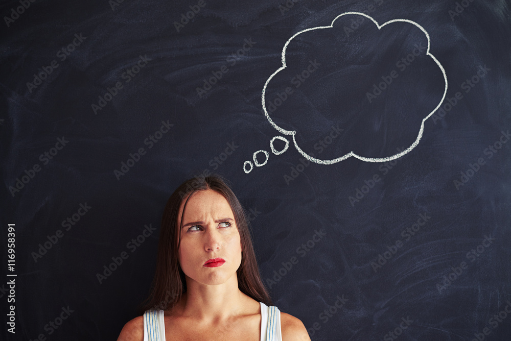 Young woman standing and frowning her brows thoughtfully