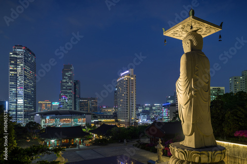 Mireuk Daebul statue (The Great Statue of Maitreya Buddha) at the Bongeunsa Temple and view of Gangnam in Seoul, South Korea at night.