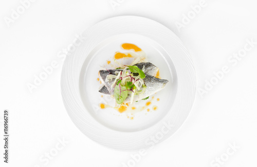 Dorado fish with grapefruit and green salad on a plate on a white background, top view
