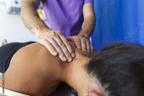 Fisioterapeuta trabajando los hombros de una joven deportista. Quiromasajista terapéutico trabajando. Tratamiento de sobrecarga muscular.