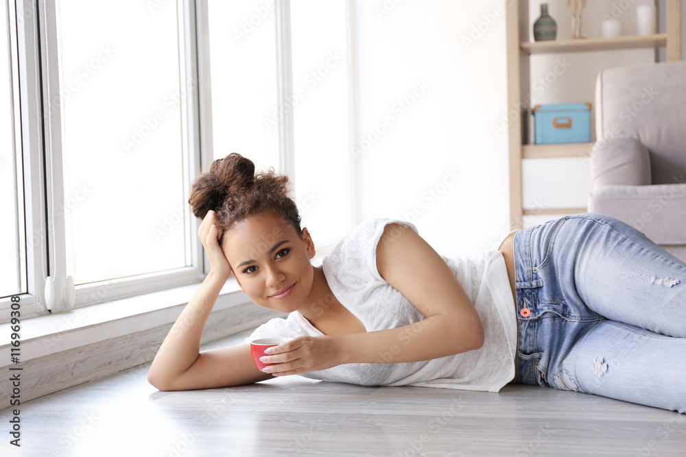 Beautiful African American girl with coffee lying on floor Beautiful African American girl with coffee lying on floor
