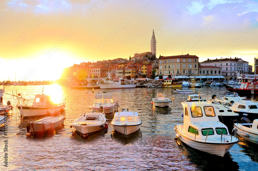 Fototapeta premium Old Town and harbor with boats and vibrant sunset over the sea, Rovinj, Croatia